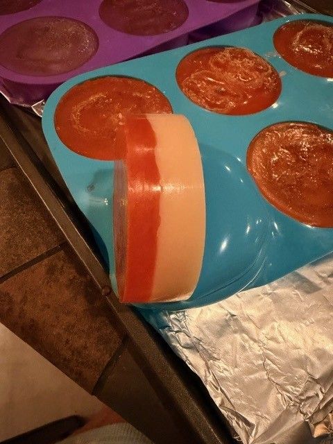 An orange and cream layered luffa soap bar on a blue mold